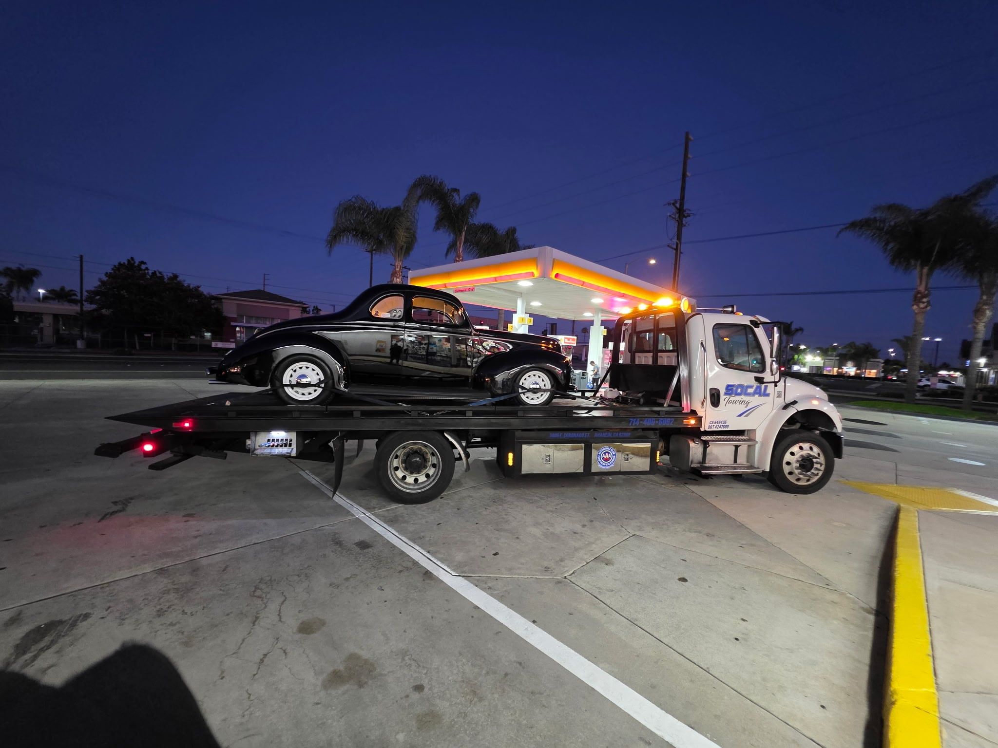 Classic coupe on a SoCal Towing flatbed at night